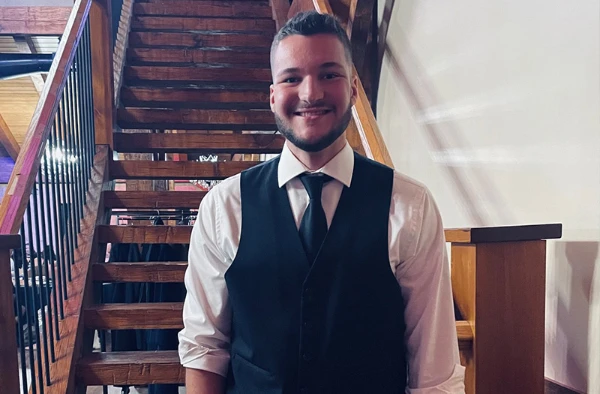 A young man in front of a staircase.